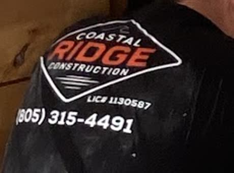 The Coastal Ridge Construction diamond logo on the shoulder of a black work shirt, above LIC# 1130587 and (805) 315-4491.