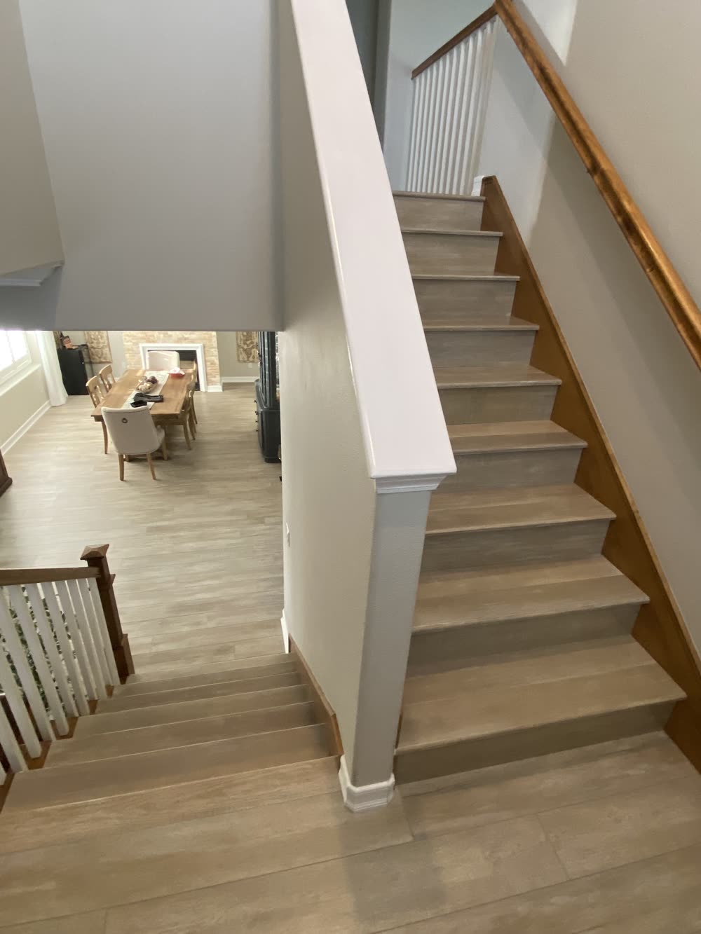 A staircase in wood-look plank matching the floor below, with a white-painted newel wall and a wood handrail.